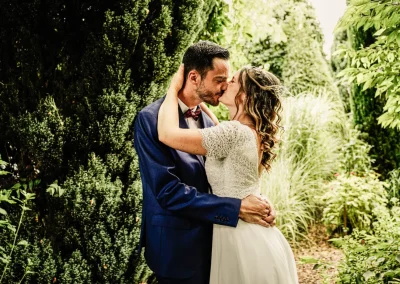 Jeune couple s'embrassant passionnément dans un jardin ensoleillé du sud de l'Auvergne Rhône-Alpes, capturant l'instant magique de leur amour.